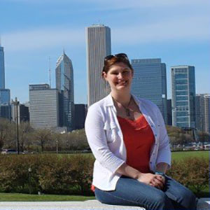 Courtney Stanford sitting and smiling at the camera with a city view in the background.